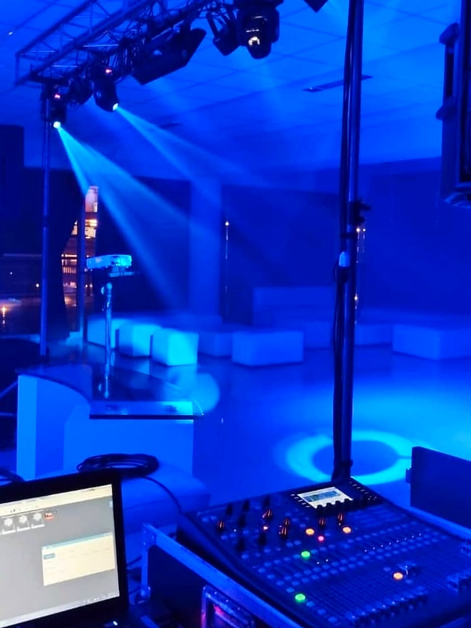 Consola de sonido e iluminación con cabezas móviles en un salón preparado para fiesta