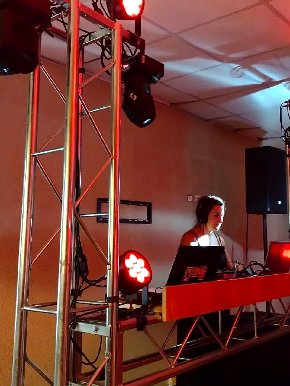 Cabina de DJ con torres de truss, cabezas móviles y par LED rojos