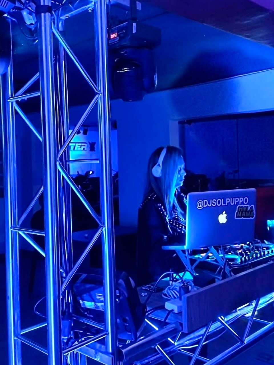 DJ en cabina de truss con cabezas móviles e iluminación azul